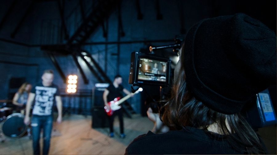 Camera filming a music video for a band performing on stage