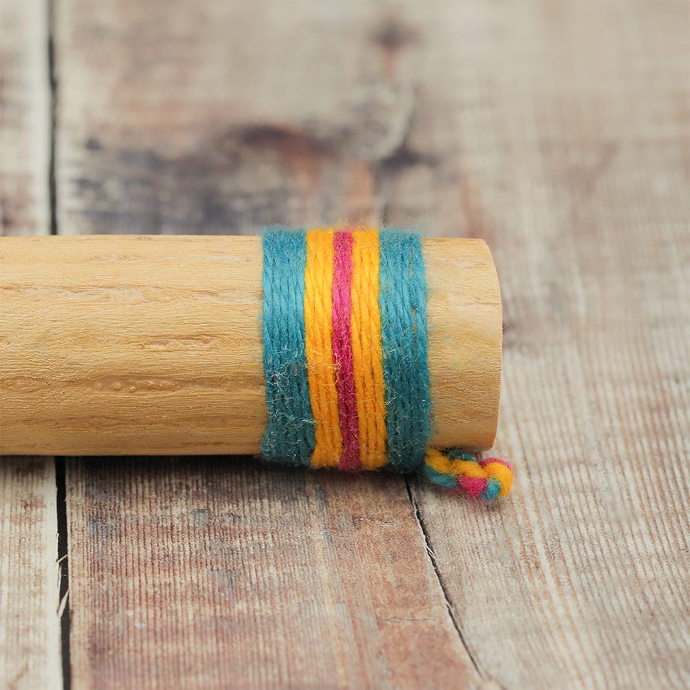 Close-up of the end of a cactus rainstick rain maker instrument, highlighting the colourful woven band wrapping around the end.