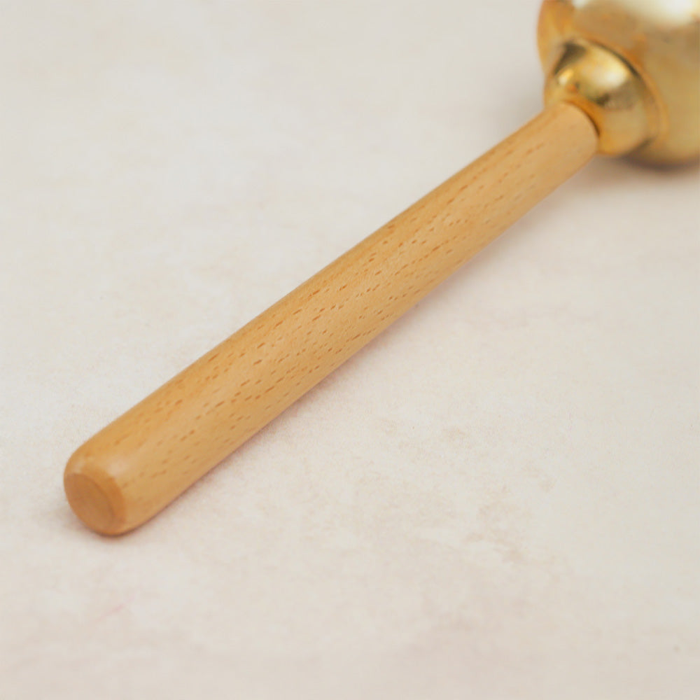 Close-up of the wooden handle of a Matsu brass bell, showcasing its smooth texture and natural wood finish.