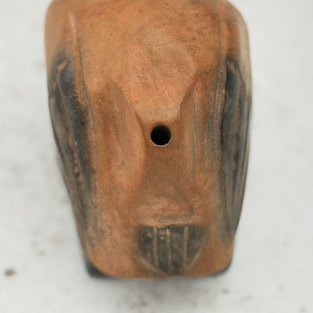 Close-up of the back end of a handcrafted wooden dodo bird whistle, showing the whistle opening.