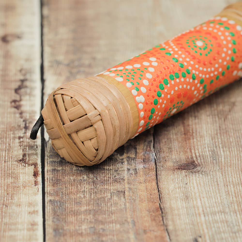 Close-up of a 15cm bamboo rainstick shaker featuring orange, green, and white dot-painted design, with a loop at the end.