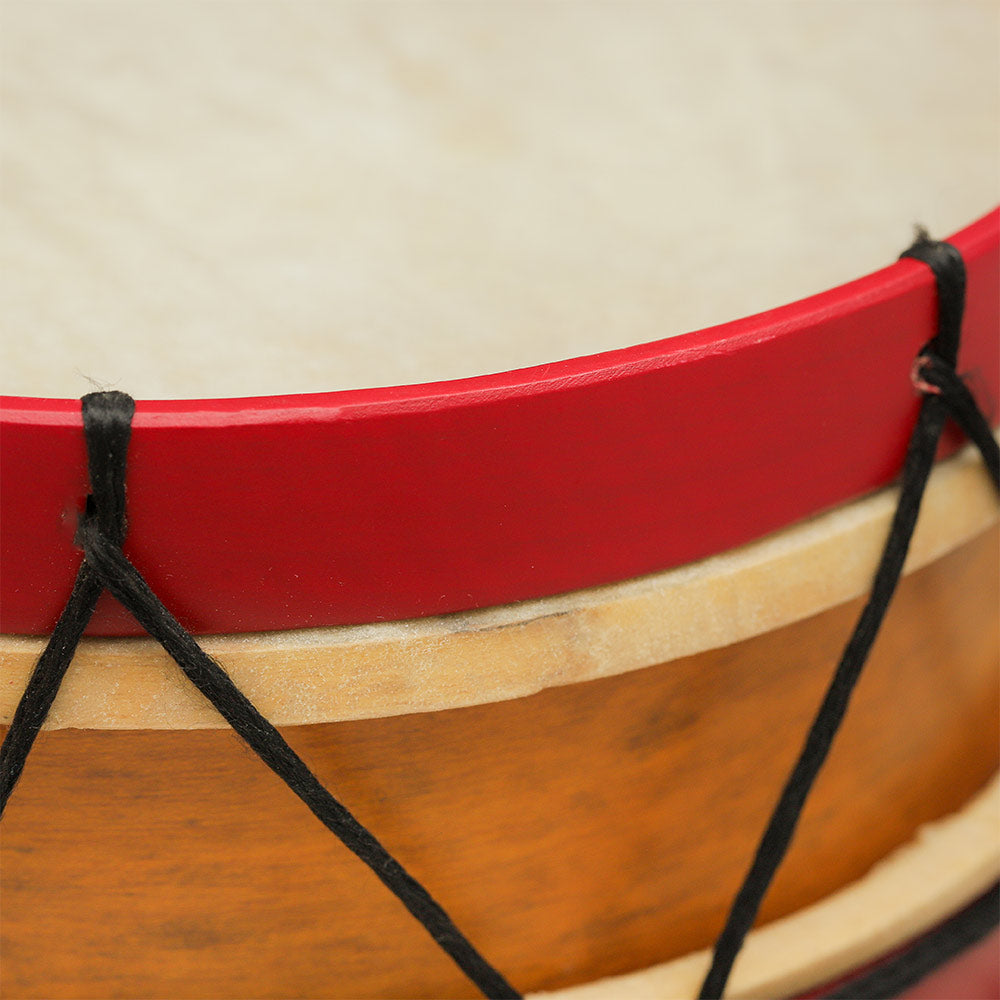 Close-up view of the wooden frame, drum hide, and rope ties of the Rattlesnake Percussion red marching drum.