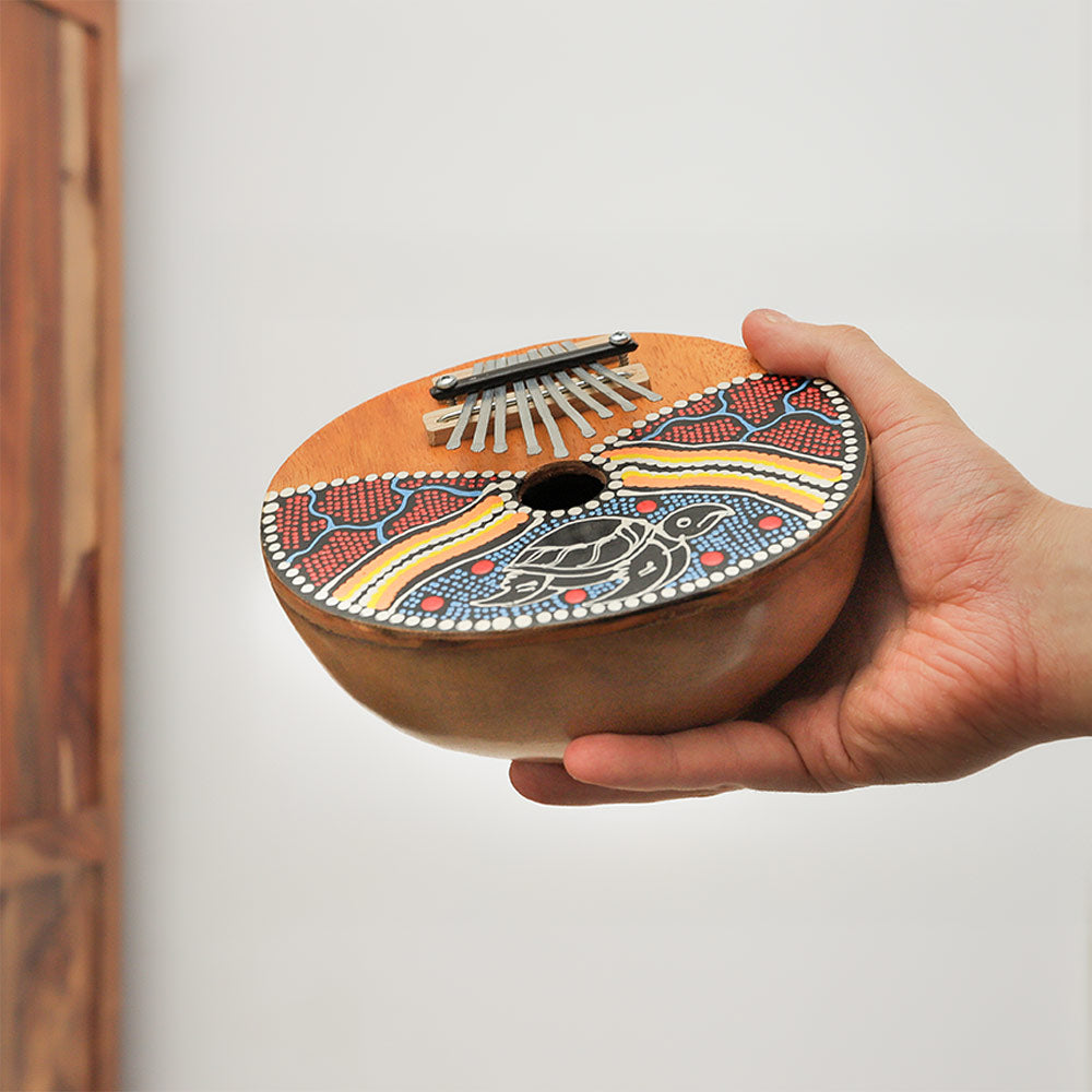 Gourd thumb piano kalimba with 9 notes and dot painted design held in hand to show scale.