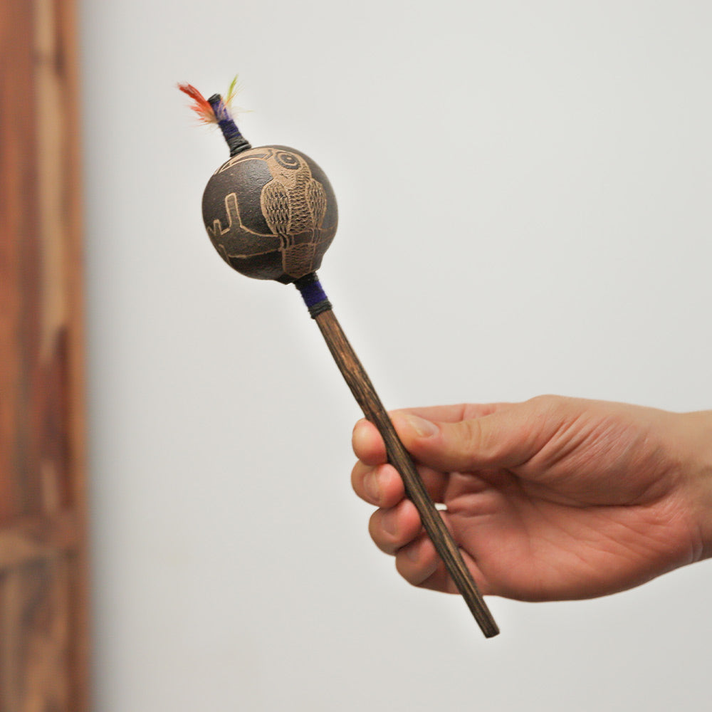 Handheld Peruvian Shipibo shaker with a carved bird design and chonta wood handle.