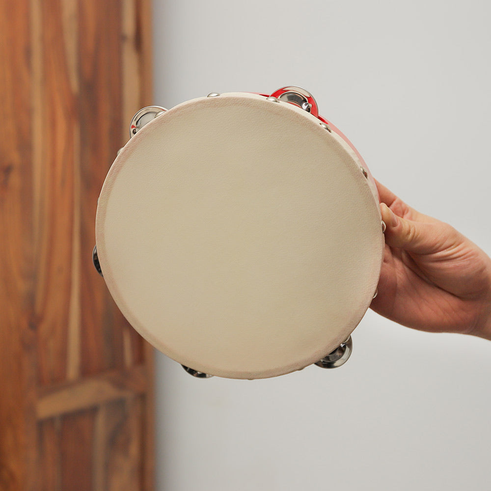 Red Pyara tambourine percussion instrument held in hand to show its scale.