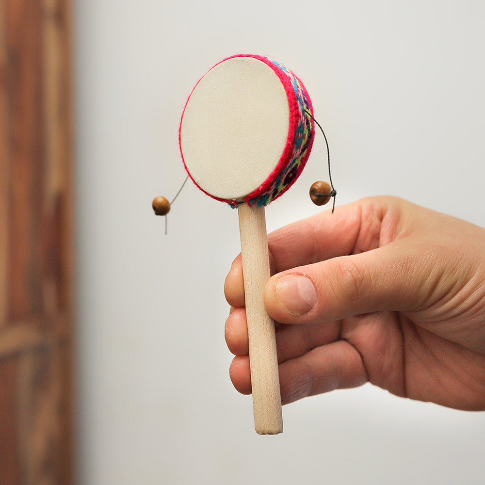 Close-up of a small Peruvian monkey drum with fabric around the drumhead, held in hand to show scale