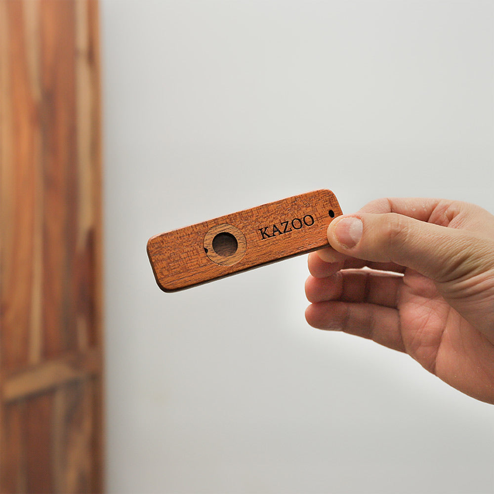 Wooden kazoo woodwind instrument held in hand to show scale.